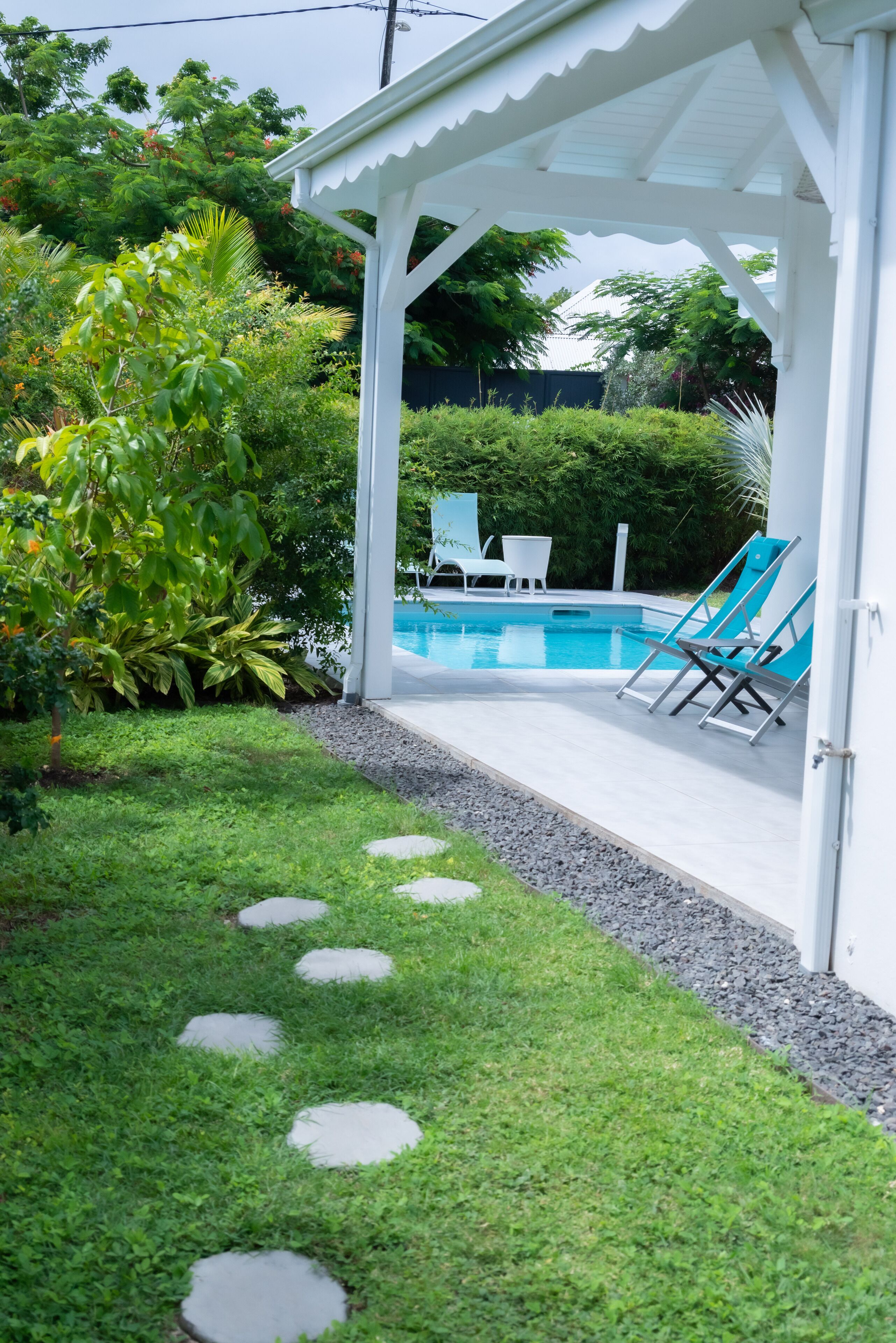 A covered outdoor area with a pool, stone steps, and lounge chairs.