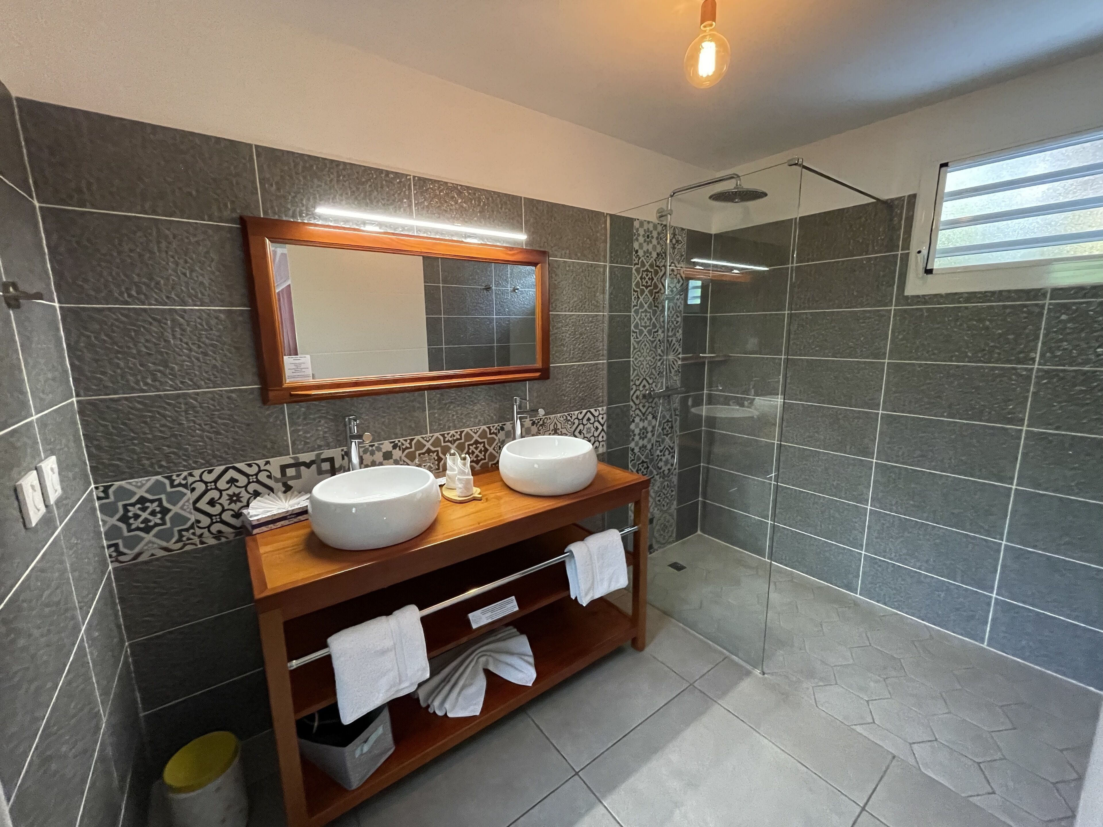 Ein modernes Badezimmer mit zwei Waschbecken, einer Dusche und einem großen Spiegel.