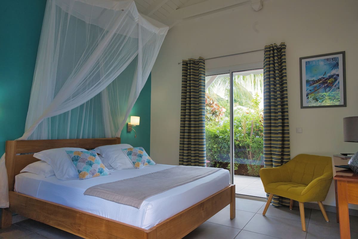 A bedroom with a bed, a chair, a window with curtains, and a poster on the wall.
