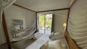 A four-poster bed with a canopy, a television on the wall, and a view of the outdoors. - Le Cocotel (Saint-François)