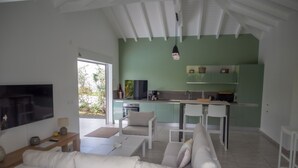 A modern living room with a sofa, a TV, and a dining area. - Le Cocotel (Saint-François)