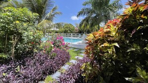 A pool area surrounded by lush tropical plants and palm trees. - Le Cocotel (Saint-François)