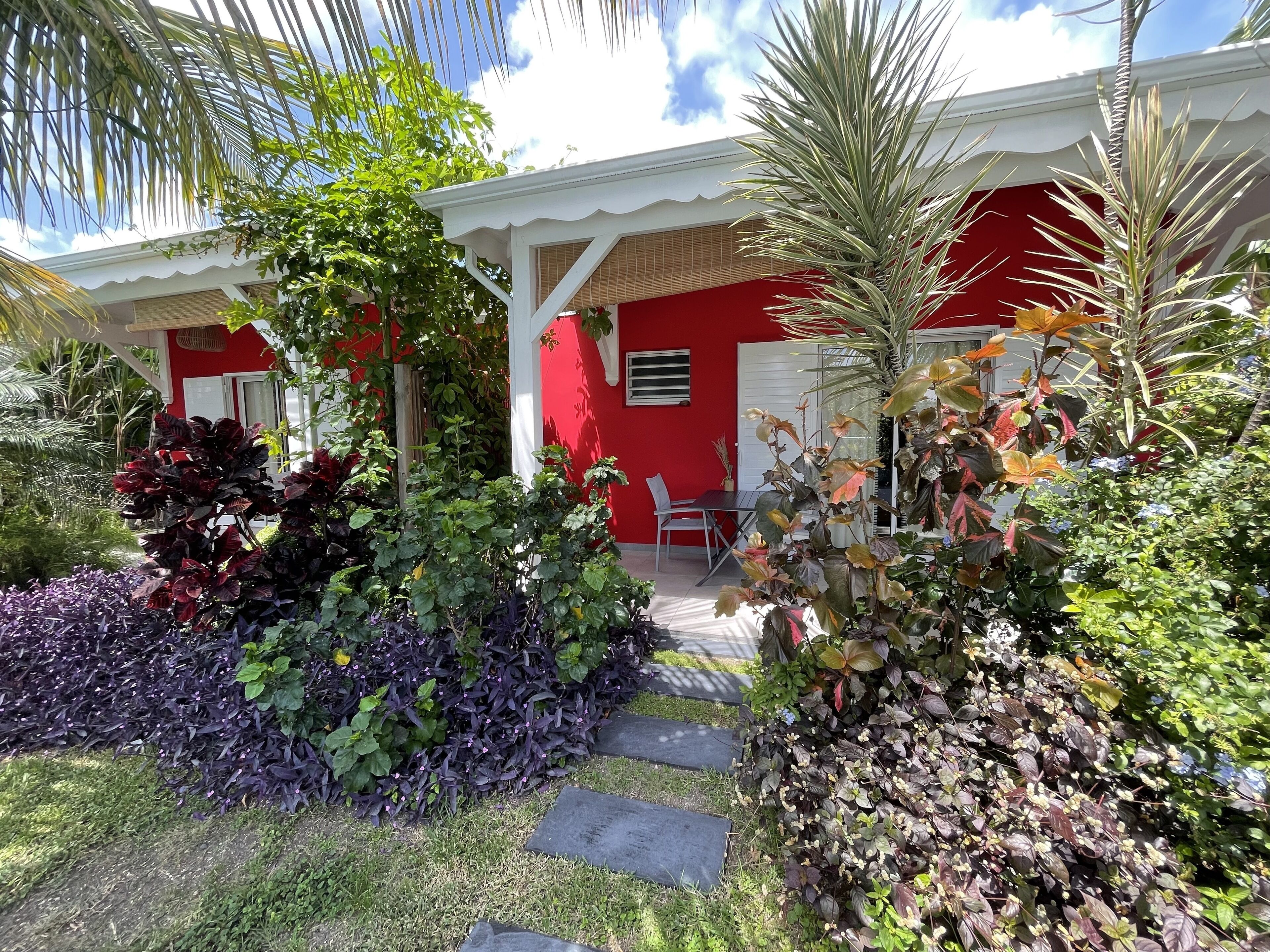 Un bâtiment rouge avec un porche blanc et une petite table et une chaise placées à l’extérieur.