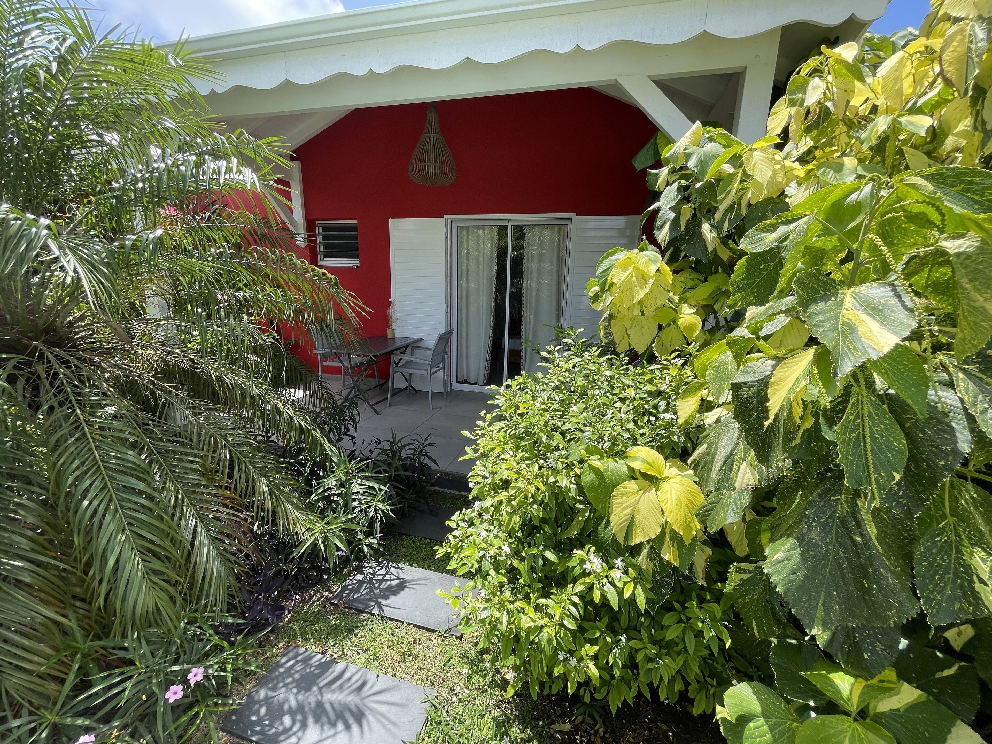 Un bâtiment rouge doté d’un patio couvert, d’un luminaire suspendu et d’une table avec des chaises.