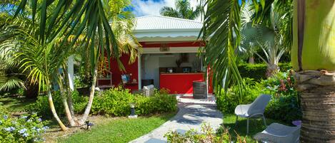 A red building with a white roof, surrounded by lush greenery and palm trees.