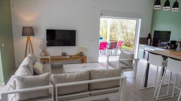 A modern living room with a sofa, TV, and dining area.