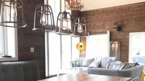 Un espace de repas moderne avec une table et des chaises en bois, un canapé et des luminaires suspendus.
