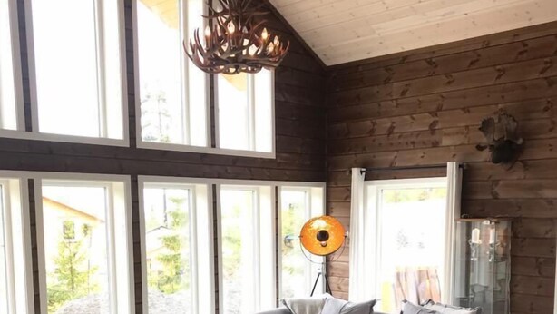 Un salon moderne avec un canapé gris, une table basse en verre et un lustre.