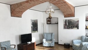 A living room with a TV, two patterned chairs, a red rug, and brick arches on the ceiling. - Bed & Roses "Gege"   (La Morra)