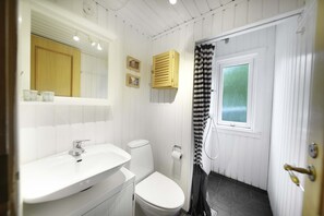 Un baño con lavamanos blanco, inodoro y cortina de ducha.