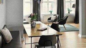 Un'elegante sala da pranzo con un tavolo lungo, sedie nere, un vaso con fiori e una lampada a sospensione.