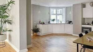 Una cucina moderna con mobili bianchi, pavimento in legno e luci a sospensione.