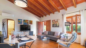 Una sala de estar con un sofá, una mesa de comedor con sillas, un televisor y obras de arte en las paredes.