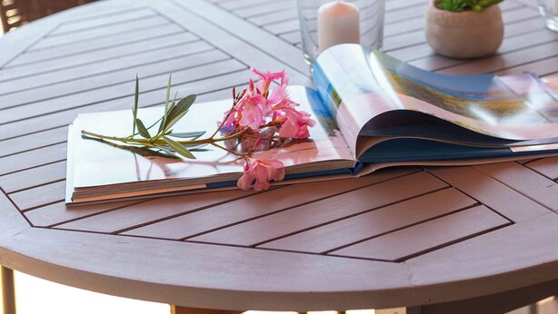 Una mesa redonda con una revista, una vela y una pequeña planta en maceta.