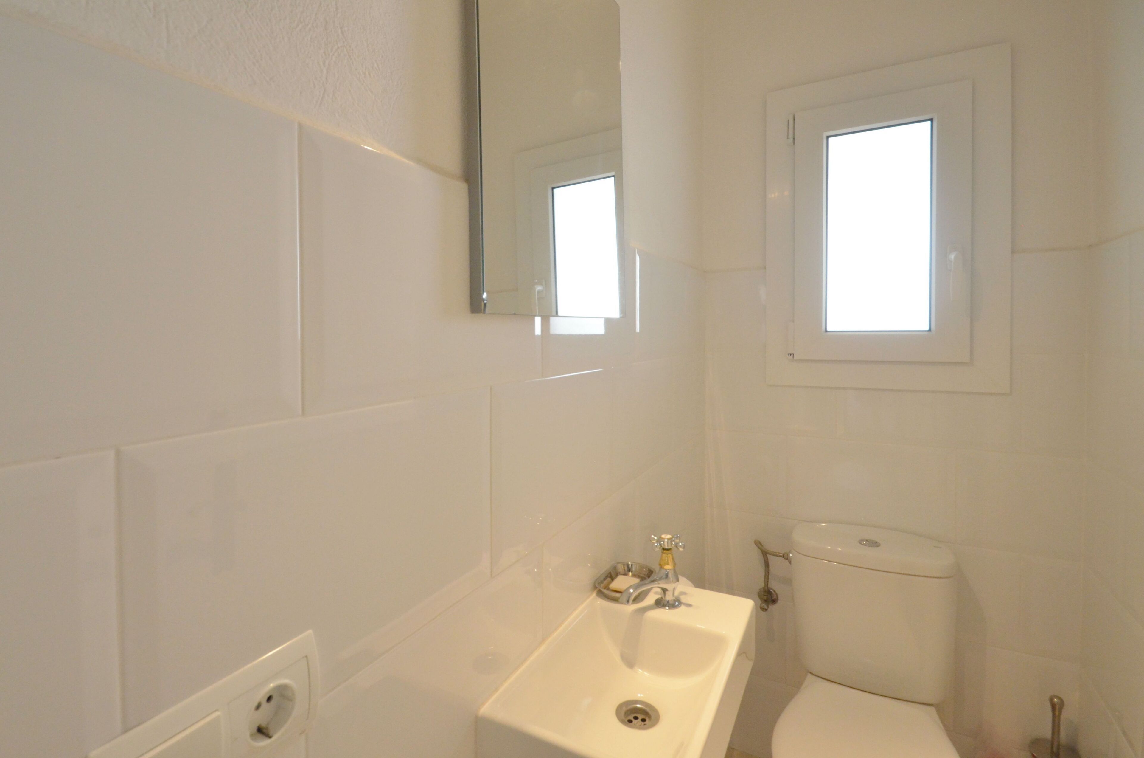 Un baño con lavamanos blanco, inodoro y espejo.