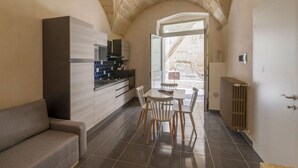 Una cocina compacta con electrodomésticos modernos, un comedor con sillas de madera y un sofá acogedor.