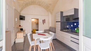 Una cocina compacta con comedor, televisor montado en la pared y salpicadero de azulejos.