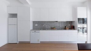 A modern kitchen with white cabinetry, a granite countertop, and stainless steel appliances. - Anna´s Flats by HostWise (Vila Nova de Gaia)