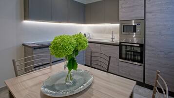 Eine moderne Küche mit integriertem Mikrowellenherd, Backofen und einer Essecke mit Tisch und Stühlen.