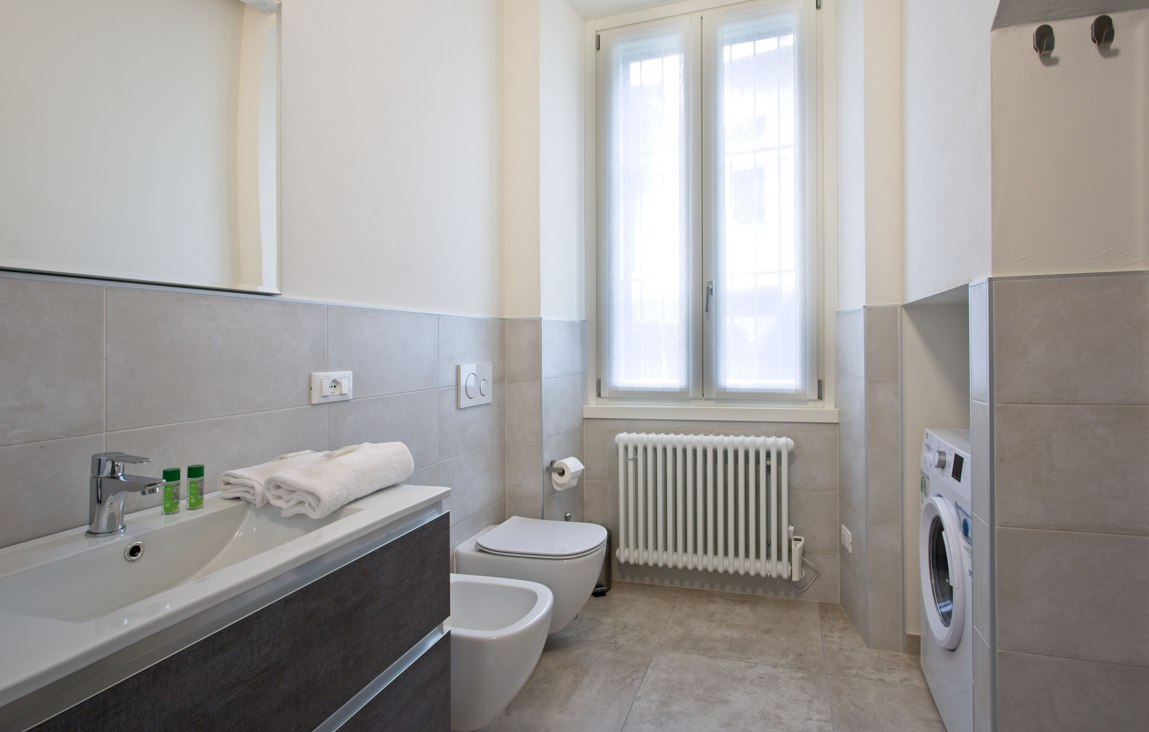 A modern bathroom with a sink, bidet, toilet, and a washing machine.