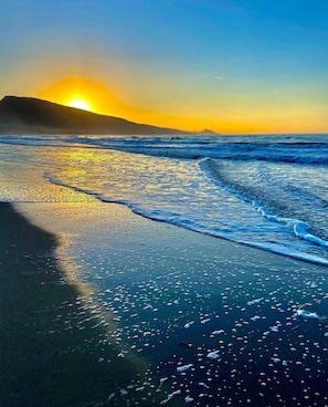 A beach scene with waves, a sunset, and a distant mountain. - New Construction,  beautiful 2 bed apartment facing the sea, Wi-fi ,Aircon (La Ciaccia)
