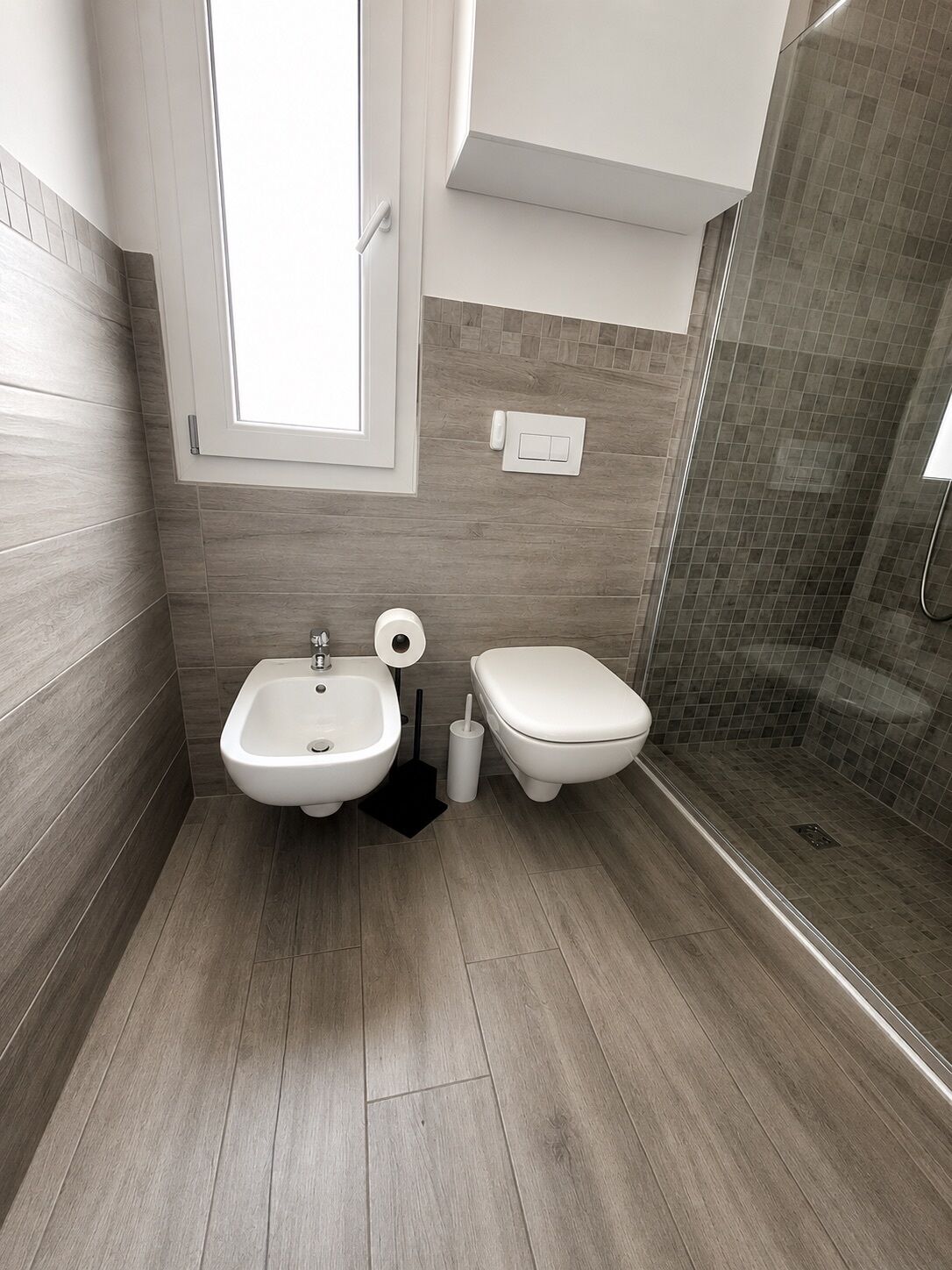 Un baño moderno con bidé, inodoro y zona de ducha.