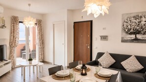 A dining area with a table set for four, a sofa, and a television in the background. - New Construction,  beautiful 2 bed apartment facing the sea, Wi-fi ,Aircon (La Ciaccia)