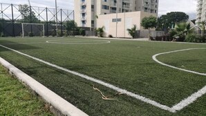 A soccer field with white boundary lines, surrounded by a fence and a building in the background. - Exclusive Vacation Apartment in Peñalisa (Ricaurte)