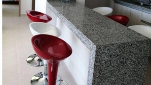A modern kitchen with a granite countertop, stainless steel sink, and red bar stools. - Exclusive Vacation Apartment in Peñalisa (Ricaurte)