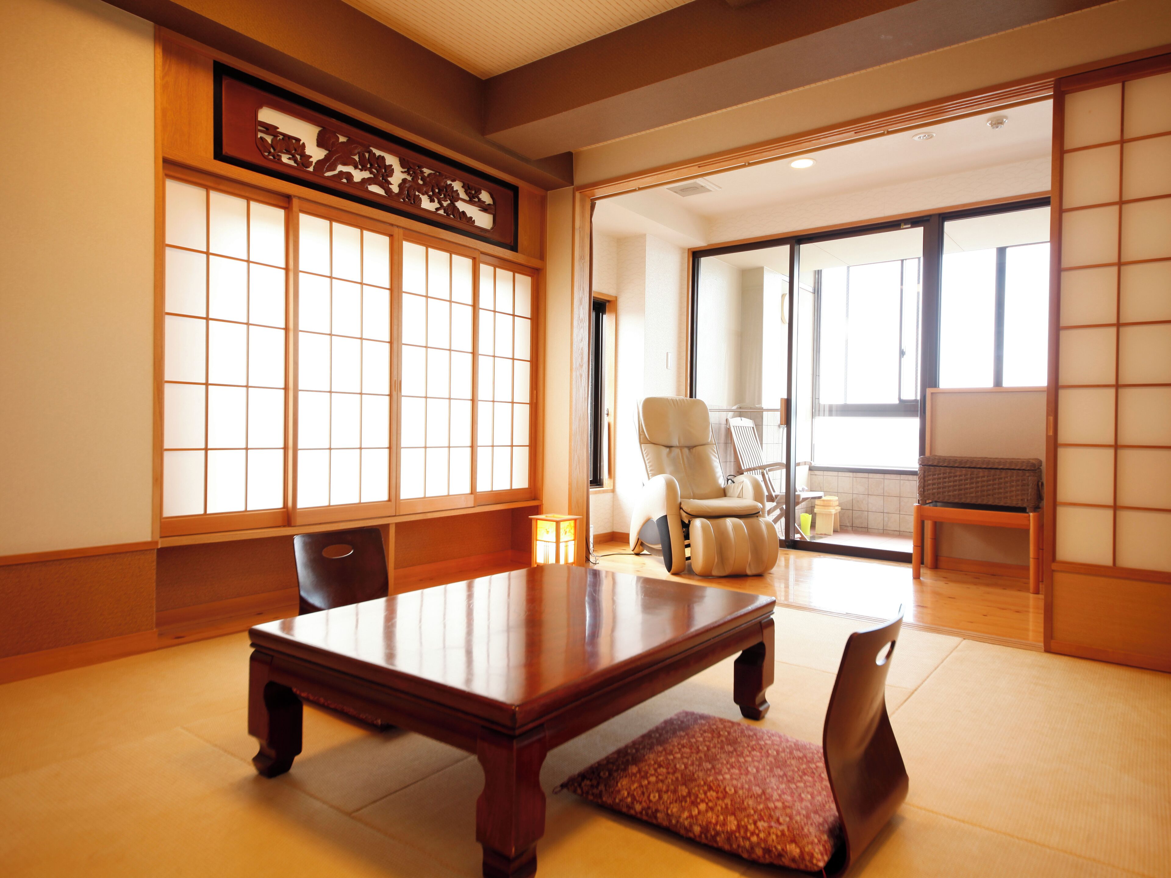 A traditional Japanese room with tatami flooring, a low wooden table, a cushioned bench, and sliding doors.
