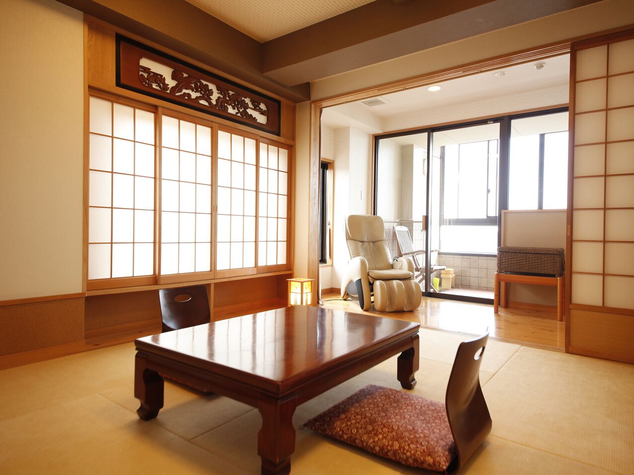 A traditional Japanese room with tatami flooring, a low wooden table, a cushioned bench, and sliding doors.