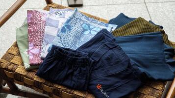 Una cistella teixida amb diverses teles i uns pantalons blau fosc sobre un terra de rajoles.