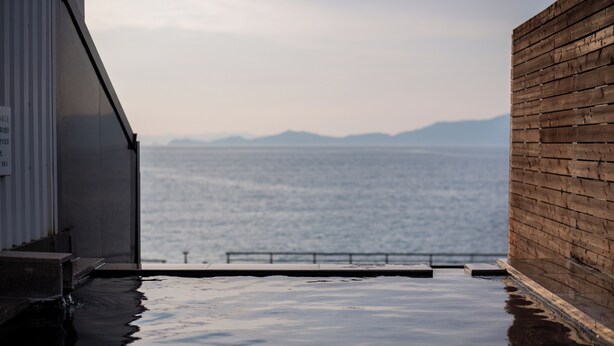 A hot tub with a view of the sea and mountains.