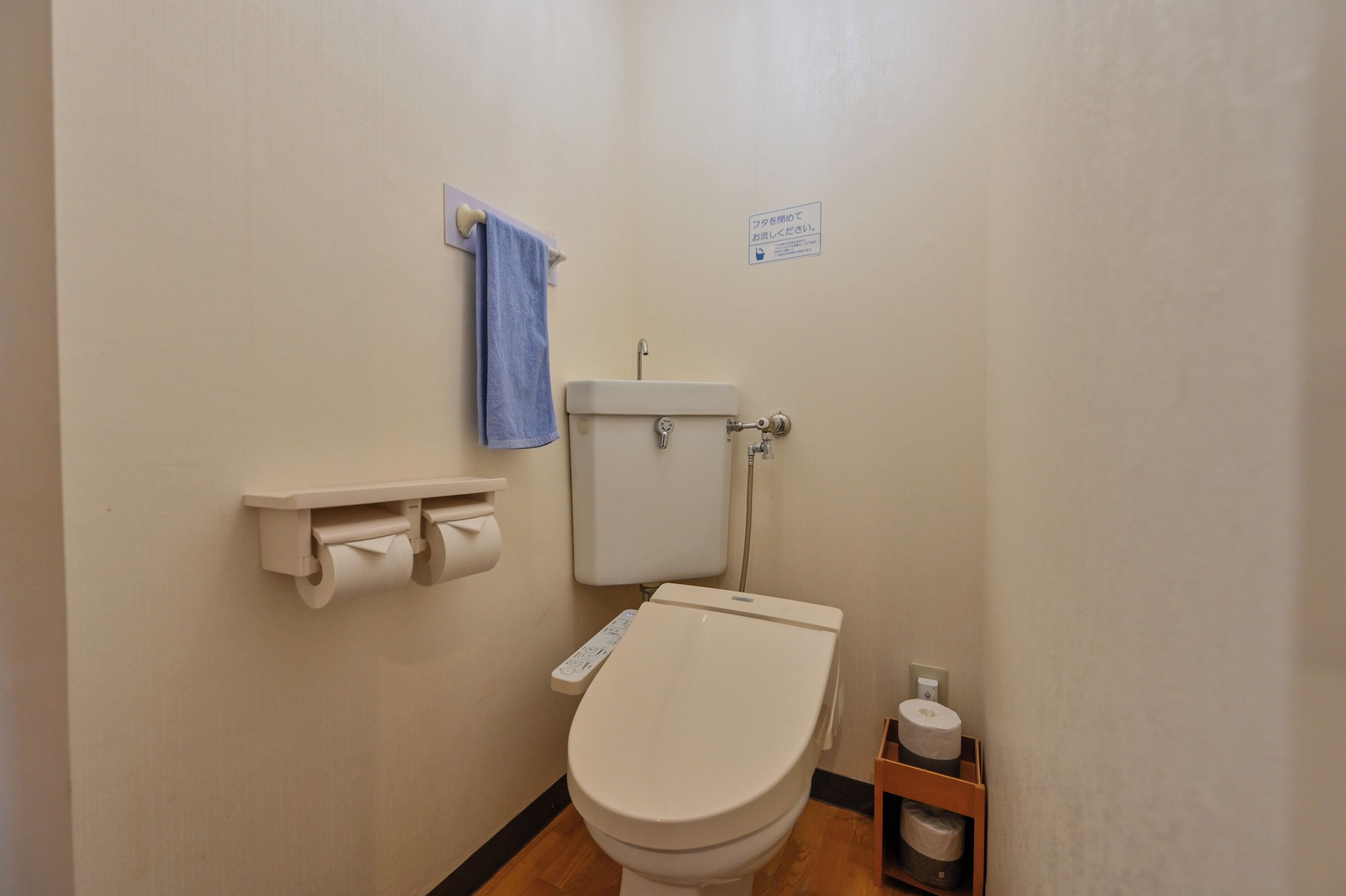 A small, clean bathroom with a toilet, a towel rack, and a toilet paper holder.