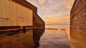 A wooden building with a sign, a pool, and a sunset view.