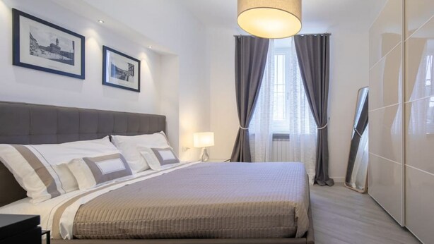 Une chambre d’hôtel avec un grand lit, une table de chevet, une lampe, une armoire et deux tableaux encadrés au mur.