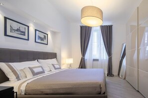 A hotel room with a large bed, a bedside table, a lamp, a wardrobe, and two framed pictures on the wall. - Palace Downtown Florence (Firenze)