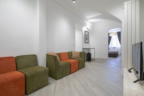 Ein modernes Wohnzimmer mit einer Sofagarnitur, einem Fernseher und einem gerahmten Bild an der Wand.