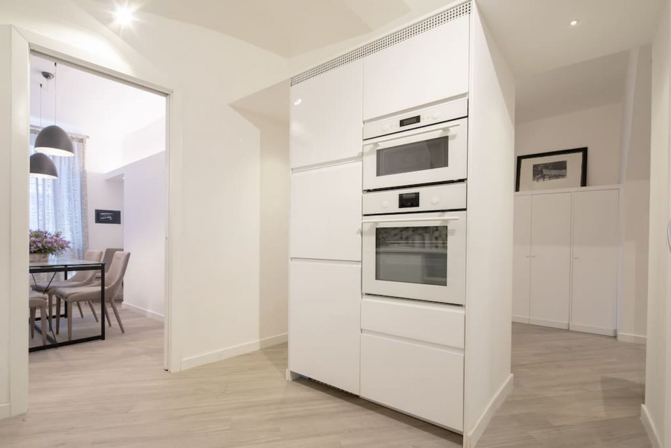 A modern kitchen with built-in ovens and a dining area with a table and chairs.