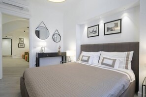 Ein modernes Hotelzimmer mit einem großen Bett, einem Schreibtisch mit Lampe und zwei gerahmten Bildern an der Wand.