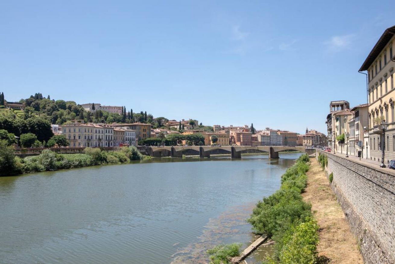 A river with buildings on the right bank and a bridge in the distance.