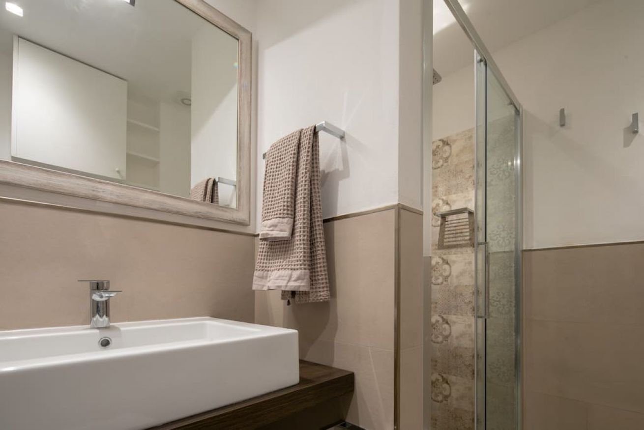 A bathroom with a white sink, a mirror, and a glass shower enclosure.