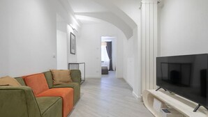 Un salon moderne avec un canapé, un téléviseur à écran plat et un couloir menant à une autre pièce.