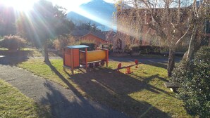 A playground with a yellow play structure, a red bench, and a small shed. - Lake view and waterfall view (Bellano)