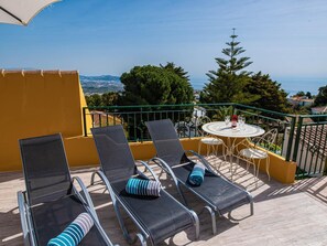 A balcony with four lounge chairs, a small round table with chairs, and a view of the sea and distant landscape. - Cosy holiday home with private pool in Salobreña (Salobreña)