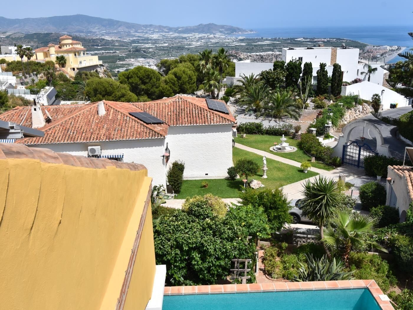 A residential area with a swimming pool, a fountain, and a view of the sea.
