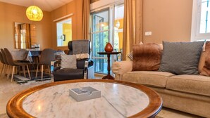 Una sala de estar con una mesa de centro de mármol, un sofá y un comedor con sillas y una mesa.