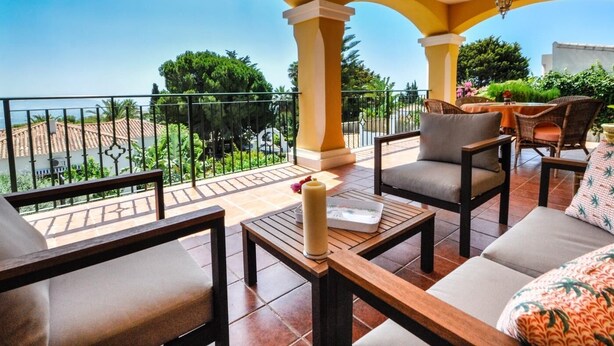 Un balcón con vistas a una zona residencial, amueblado con un sofá, sillas y una mesa.