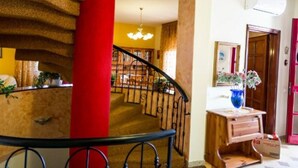 Eine Treppe mit einer roten Säule, ein Holztisch mit einem Blumenstrauß und ein Spiegel an der Wand.