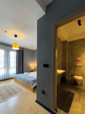 A modern hotel room with a bed, bedside table, lamp, and a view of the bathroom. - La Kalinda Bozcaada (Bozcaada)